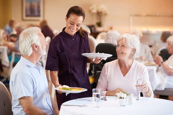 Staff serving dinner to residents in dining area