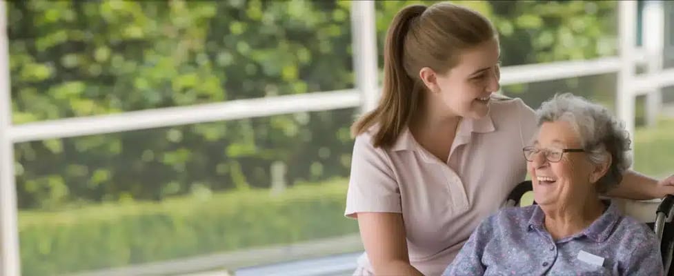 Caregiver and resident laughing together in a bright common area