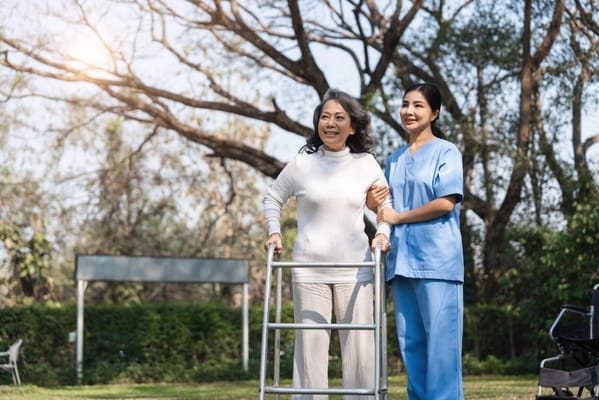 A caregiver assisting a senior woman outdoors