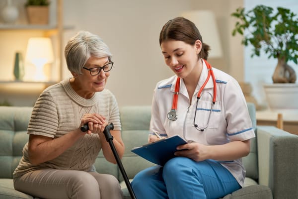 A caregiver assisting an elderly woman in a cozy room