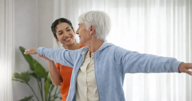 Senior resident exercising with staff member indoors