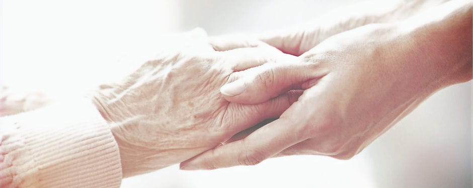 A caregiver holding the hand of a senior resident