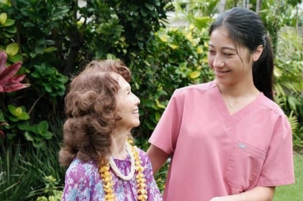 A caregiver smiling with a resident in a garden