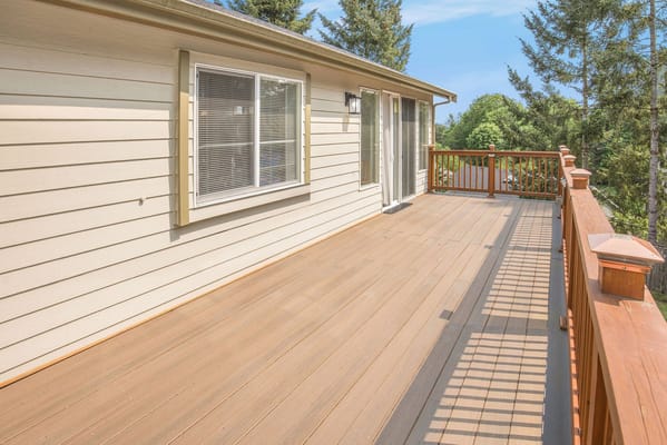 Deck area with wooden railing and trees in the background