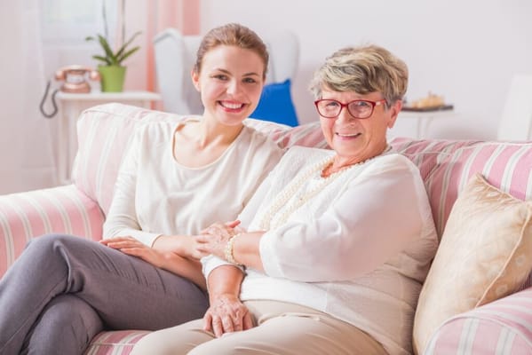 Resident and staff member smiling on a couch
