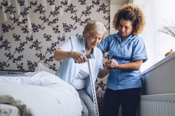 Staff assisting a resident in a bedroom