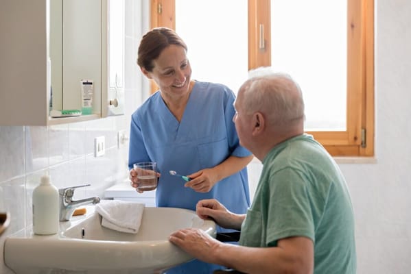A caregiver assisting a senior resident in a bathroom