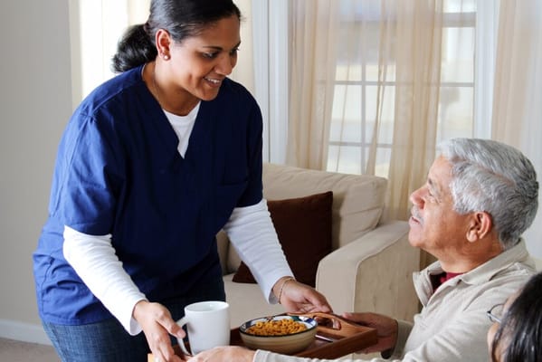 Staff serving food to a resident in a cozy indoor setting