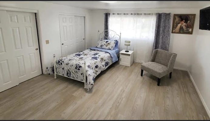 Bright resident room with a bed and chair