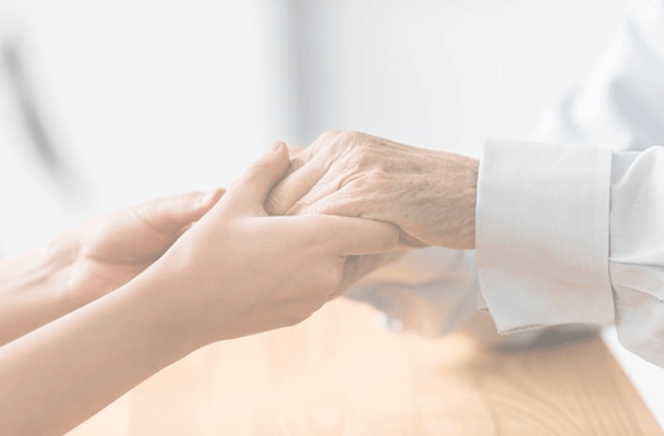 A caregiver holding an elderly person's hand
