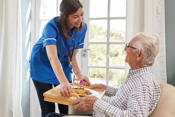 Staff serving food to a resident in a cozy room