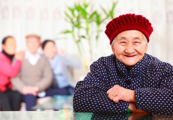 A smiling elderly woman in a cozy common area