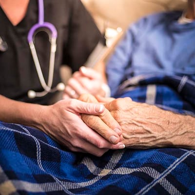 A caregiver holding a resident's hand