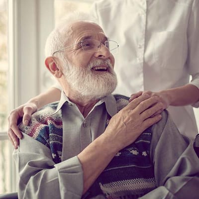 A smiling elderly man with a caregiver