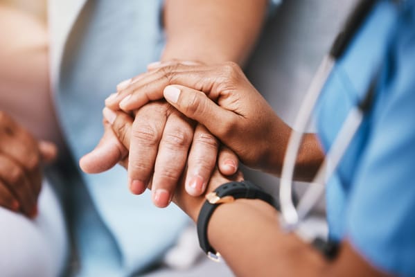 Hands of a caregiver and a senior holding each other