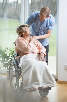 A caregiver assisting a resident in a wheelchair inside the facility