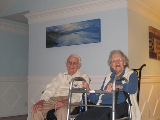 Two residents sitting in a common area with assistive devices