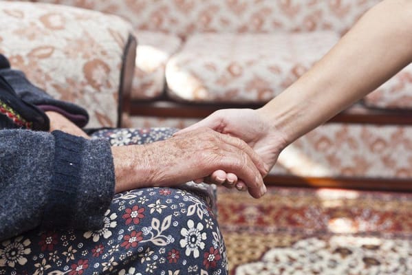 A caregiver holding an elderly person's hand