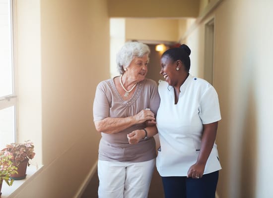 A resident and staff member laughing in a hallway