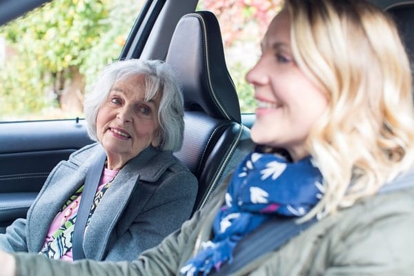 Senior woman smiling in a car with caregiver