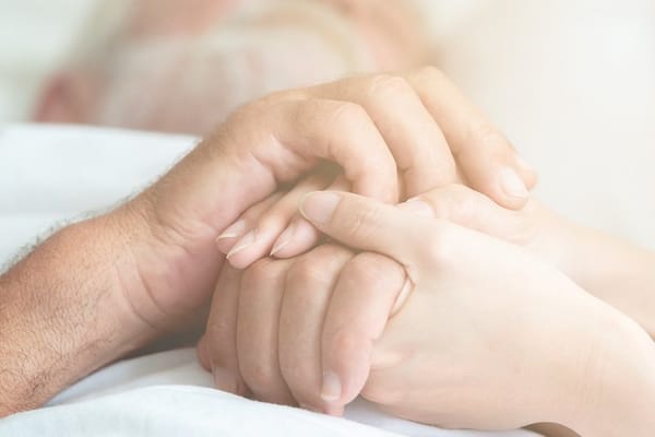 Two hands holding intimately in a soft setting