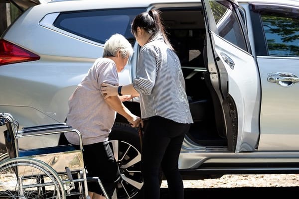 A caregiver assisting a senior resident into a vehicle