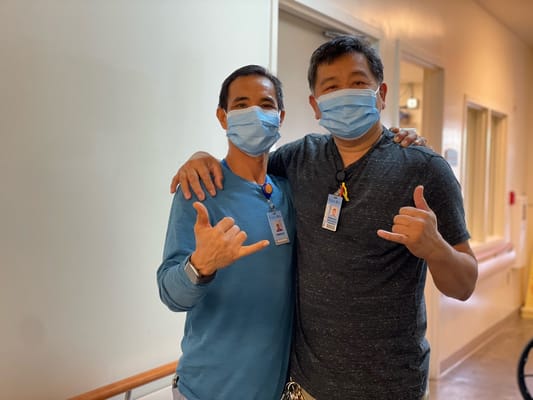 Two staff members posing with smiles in the hallway
