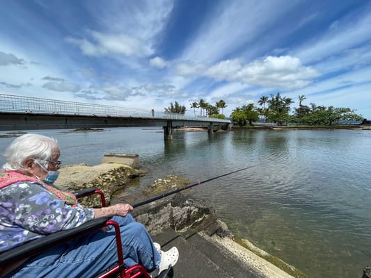 Senior resident fishing by the water in a wheelchair