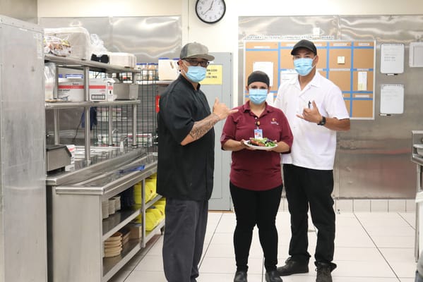 Three staff members posing in the kitchen