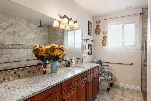 Brightly lit bathroom with floral decor and granite countertop
