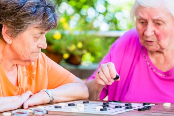 Two residents playing a board game outdoors
