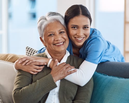 A resident and caregiver smiling together in a cozy living area