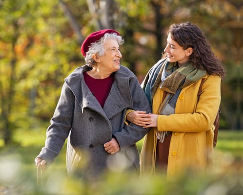 An older woman and a caregiver walking in a garden