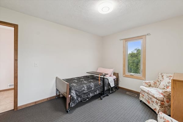 Cozy private bedroom with floral armchair and bed