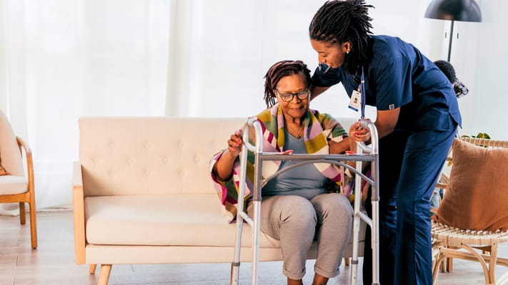 Nurse assisting a resident with a walker in a bright room