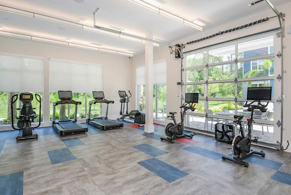 Gym equipped with treadmills and stationary bikes in a bright space