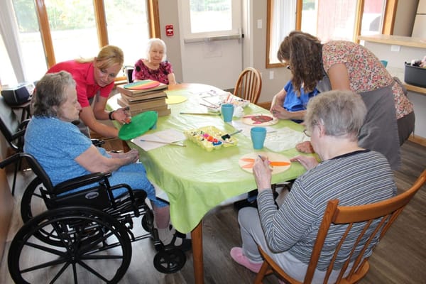 Residents engaging in a creative activity with staff assistance