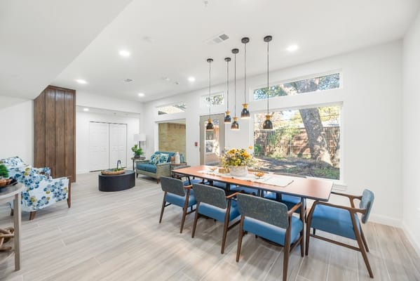 Bright common area with dining table and large windows