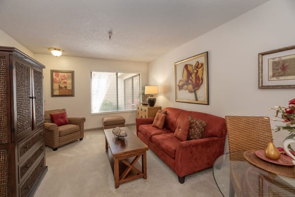 Cozy living room with orange couch and decorative paintings.