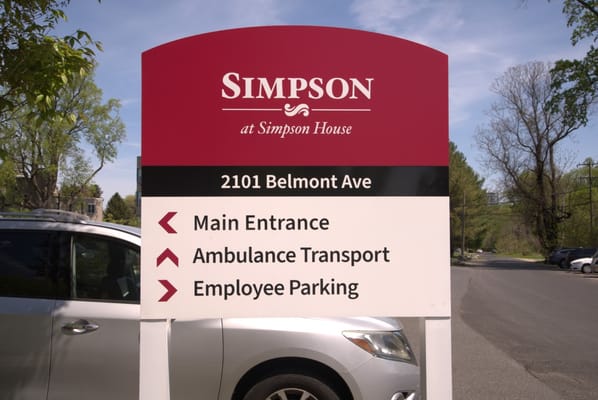 Sign indicating main entrance, ambulance transport, and employee parking at Simpson House.