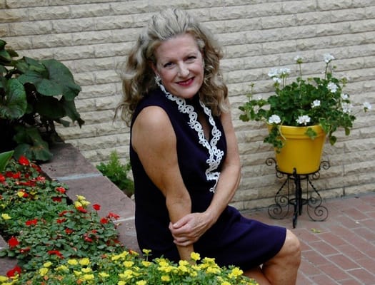 Woman sitting beside vibrant flowers in a garden setting