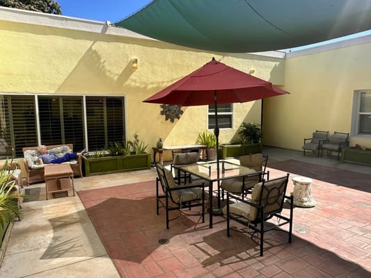 Senior resident relaxing in the courtyard under a shaded umbrella.