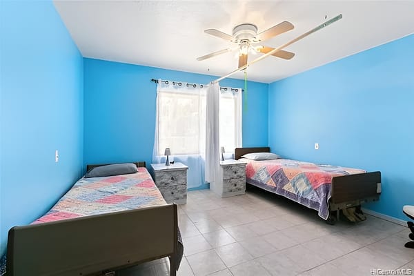 A spacious bedroom with two twin beds and blue walls.