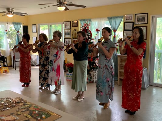 Residents dressed in traditional attire performing music indoors