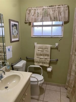A clean and well-lit bathroom with grab bars and a toilet.
