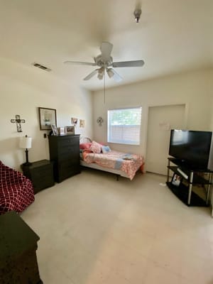 A cozy bedroom featuring a bed, dresser, and television.