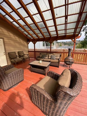 Outdoor seating area with wicker chairs and a table under a wooden pergola