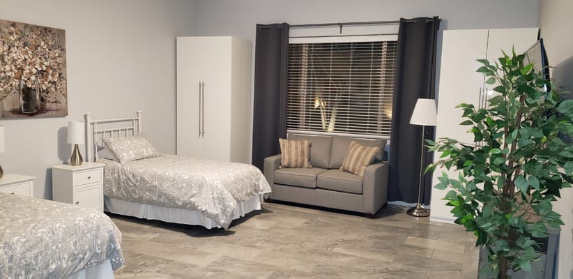 Spacious bedroom with two beds, a sofa, and natural light