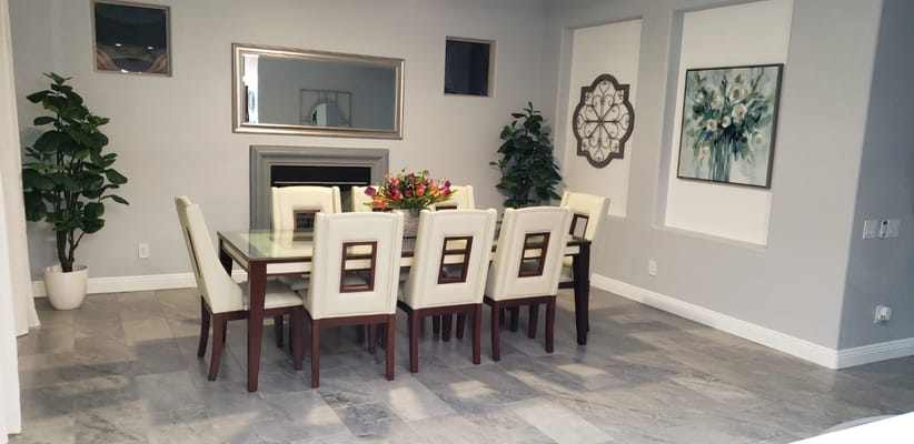 Modern dining area featuring a large table with white chairs and floral centerpiece.