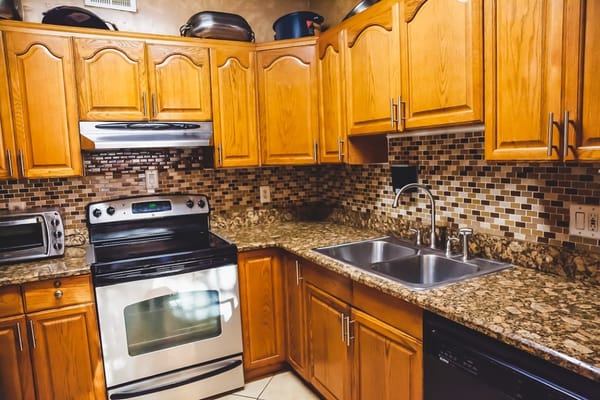 Brightly lit kitchen with wooden cabinets and granite countertops